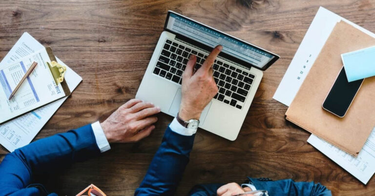 Créer une société à Malte : Homme en costume travaillant sur un ordinateur portable sur un bureau en bois