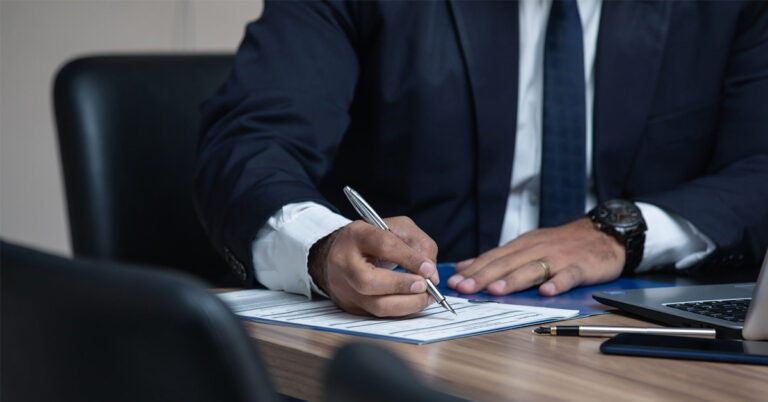 Homme en costume signant un document avec un stylo