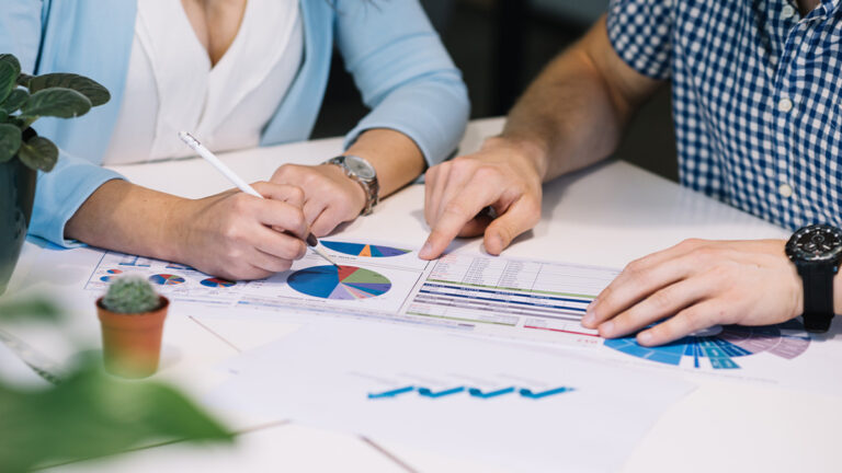 Deux personnes analysent des graphiques et des données sur un bureau